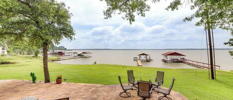 A patio with outdoor furniture overlooking a lake, a dock, and a gazebo.