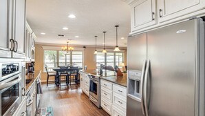 A spacious kitchen with stainless steel appliances, wooden flooring, and a dining area with a chandelier. - Waterfront Retreat w/ Dock on Cedar Creek Lake! (Kemp)
