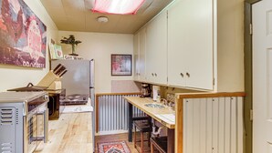 Una cocina compacta con encimera de madera, un refrigerador y un comedor con mesa y sillas.