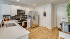 A modern kitchen with white cabinets, a stainless steel refrigerator, a microwave, and a sink. - 2 Mi to Olympic National Park: Sun-soaked Haven! (Port Angeles)