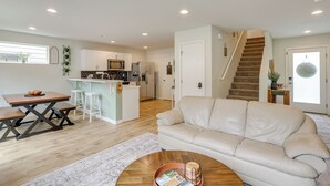 A modern living room with a beige sofa, a wooden coffee table, and a kitchen in the background. - 2 Mi to Olympic National Park: Sun-soaked Haven! (Port Angeles)