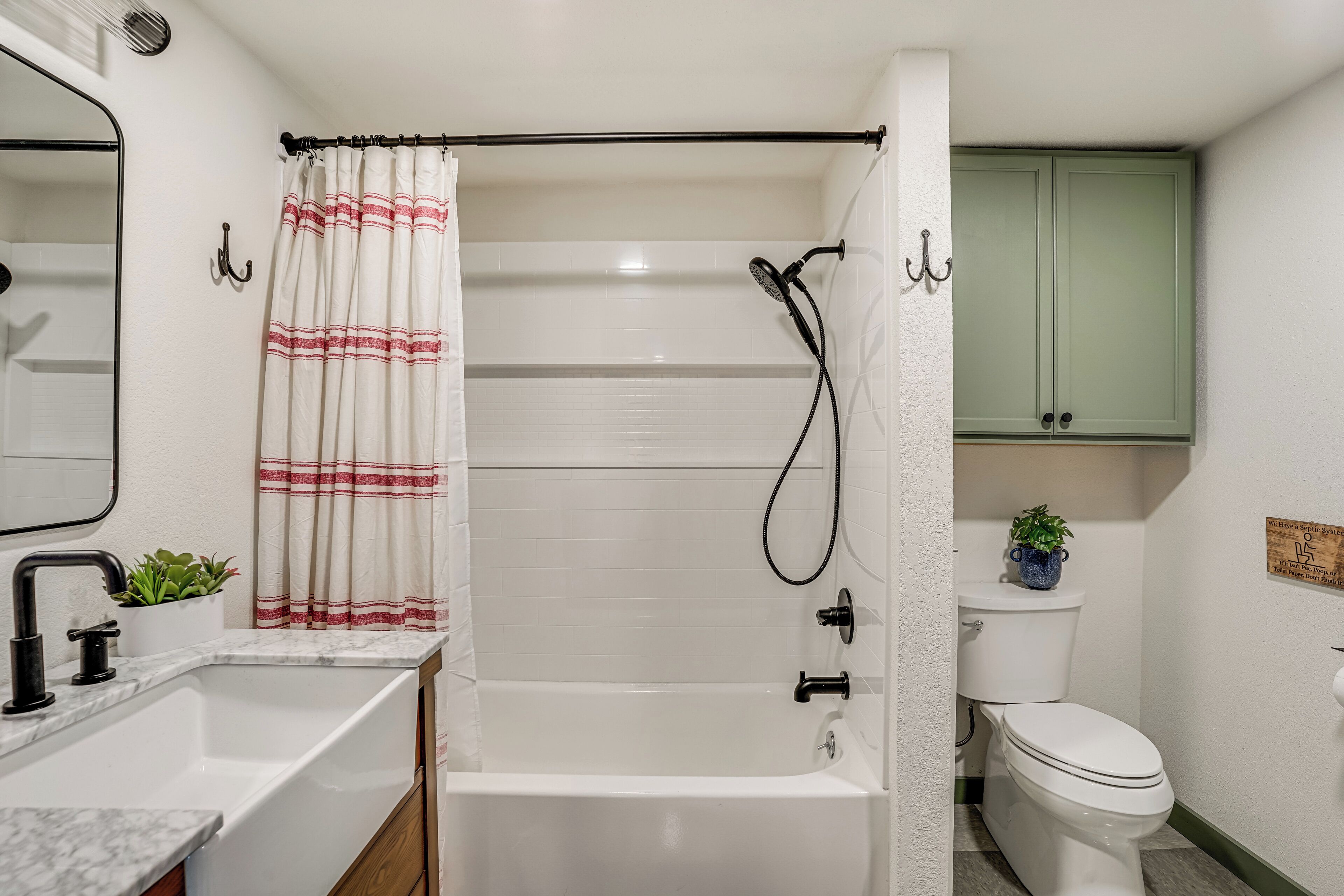 Un baño con una bañera blanca, un inodoro, un lavamanos y un armario verde.