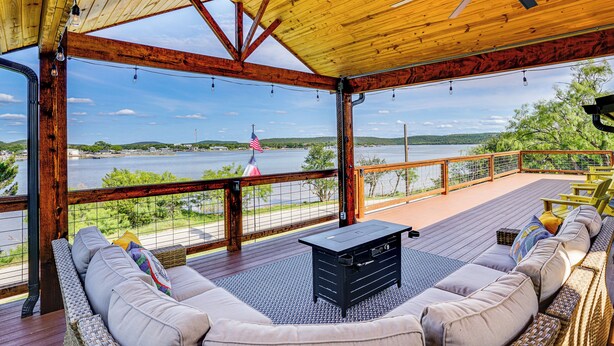 A covered deck with a view of a lake, wooden beams, and a black table. - Lake View + Huge Deck: Cozy Possum Kingdom Retreat (Graham)
