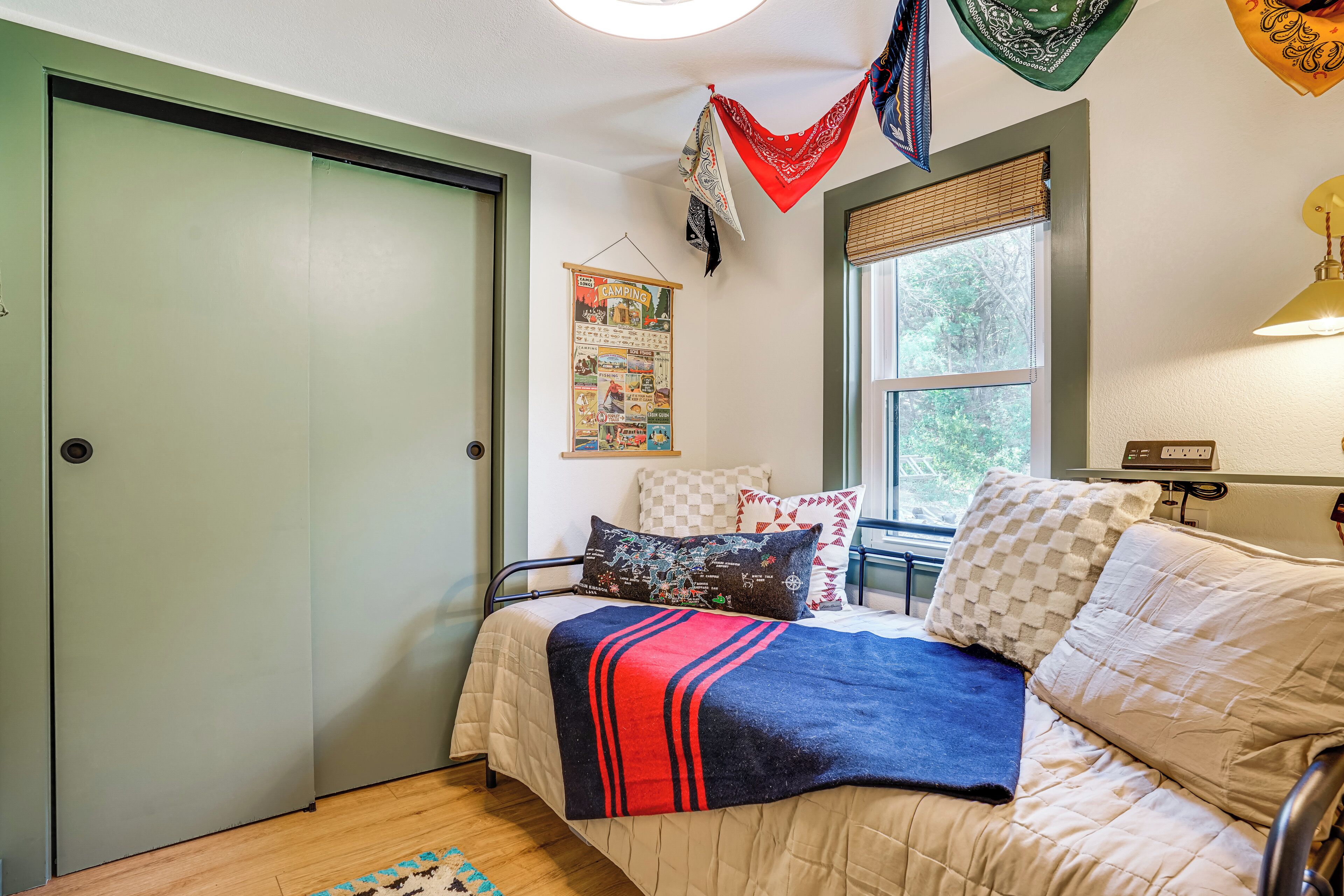 A bedroom with a bed, pillows, a blanket, a window, and a door.