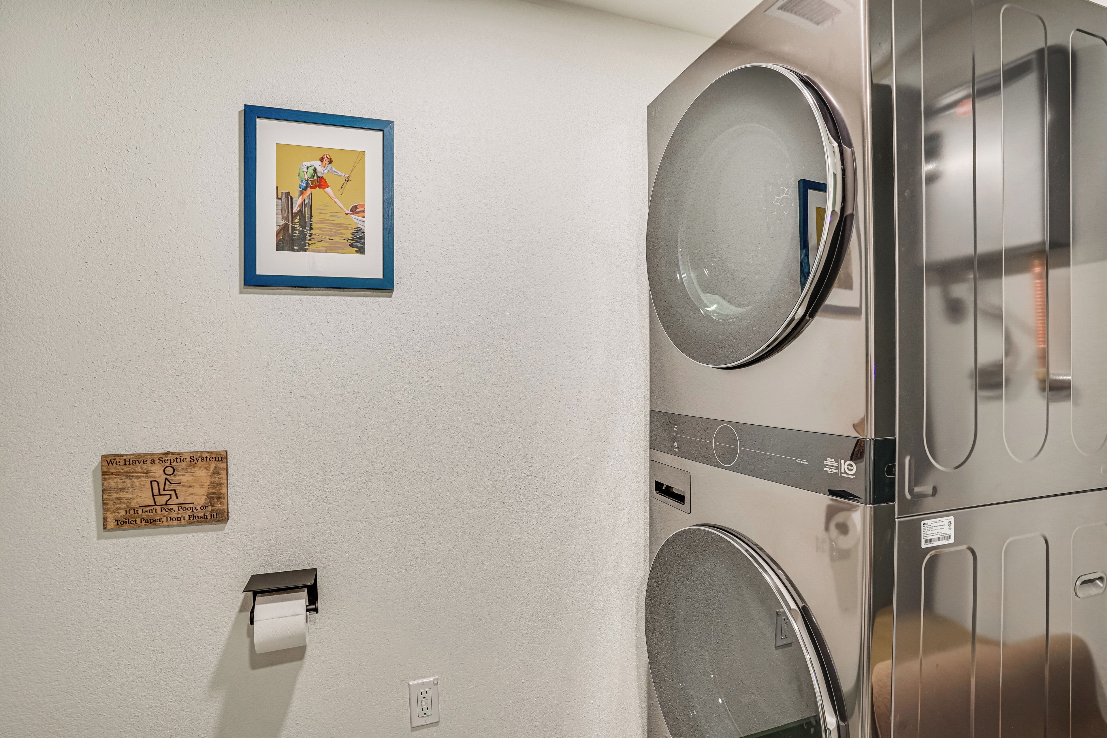 A laundry area with a sign indicating a septic system, a framed picture, and a toilet paper dispenser.
