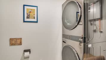 A laundry area with a sign indicating a septic system, a framed picture, and a toilet paper dispenser.