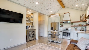 A modern kitchen with a built-in oven, a refrigerator, and a bar area with stools. - Recently Built Cabin w/ Pavilion in Granbury! (Granbury)
