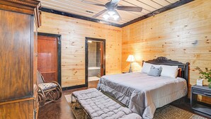 A wooden-paneled bedroom with a bed, bench, chair, and a ceiling fan. - Upscale Getaway on Smith Lake w/ Boat Dock (Houston)
