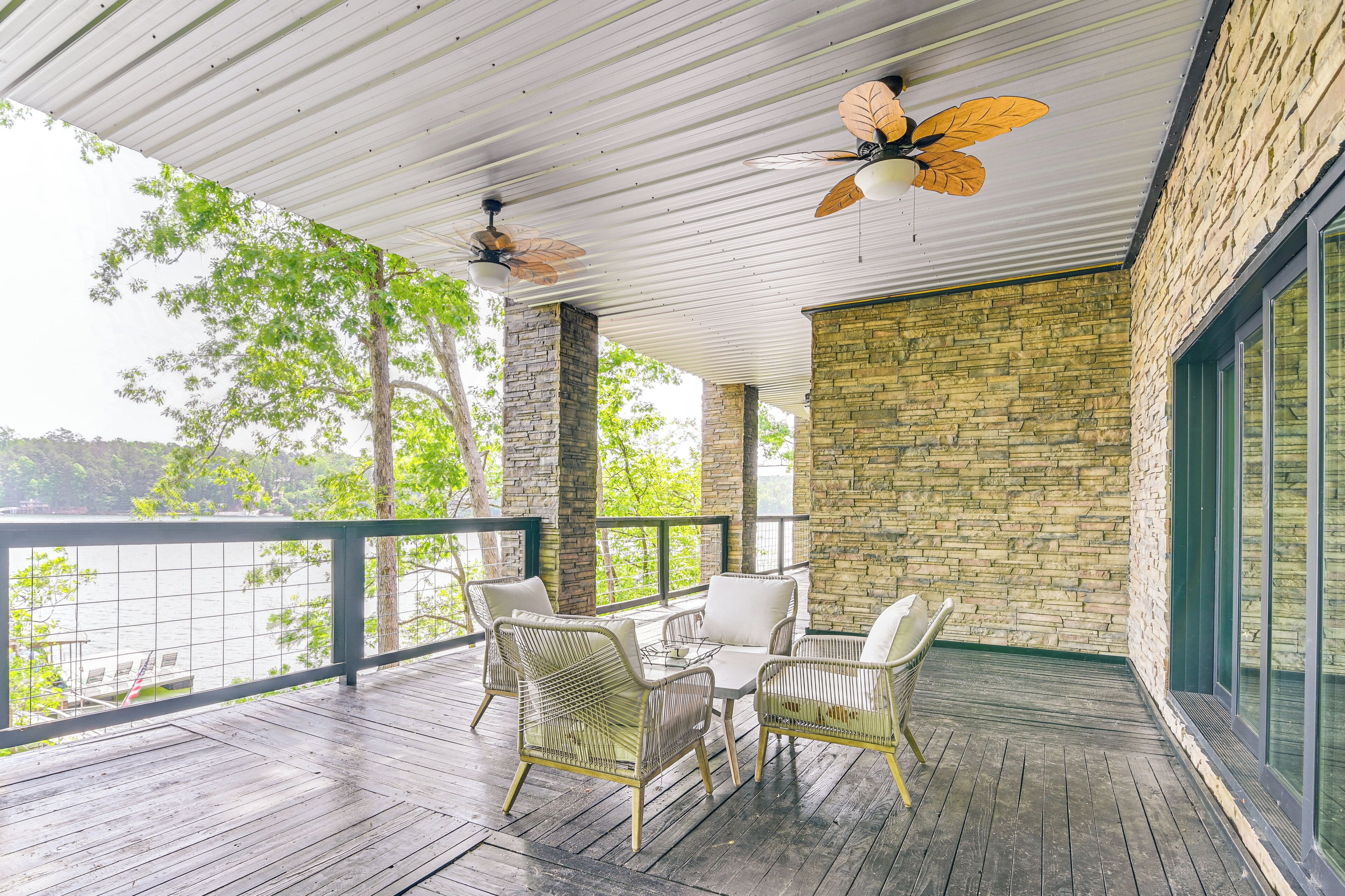 A covered outdoor area with a table and chairs, stone walls, and a view of a body of water.