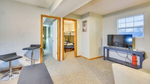 Habitación de hotel pequeña con cama, televisión, una mesita y dos taburetes.