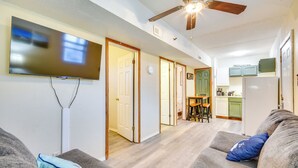 Una sala de estar con una televisión de pantalla plana, ventilador de techo y un sofá con almohadones.