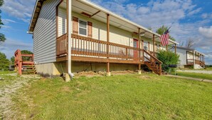 A two-story house with a porch, a small deck, and an American flag. - 1 Mi to Mark Twain Lake: Cabin w/ Community Pool (Stoutsville)
