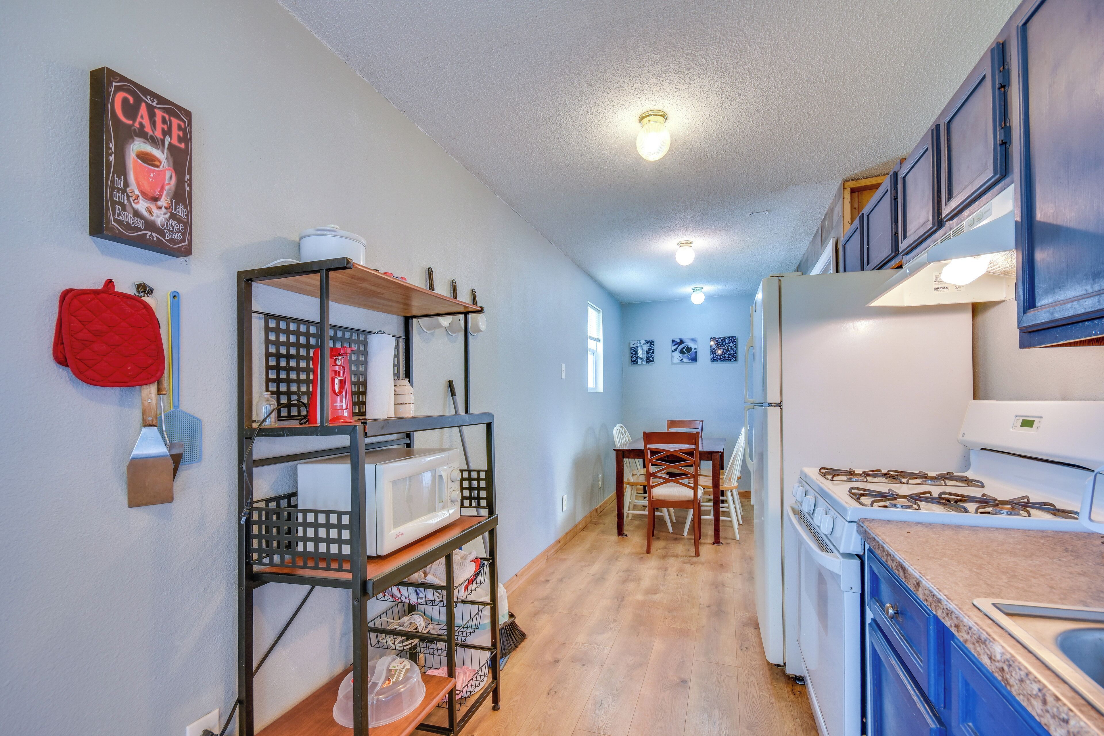 A kitchen with a stove, microwave, and a dining area with chairs and a table.