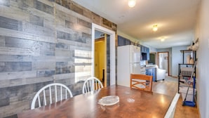 A dining area with a wooden table and chairs, a kitchen in the background, and a white refrigerator. - 1 Mi to Mark Twain Lake: Cabin w/ Community Pool (Stoutsville)