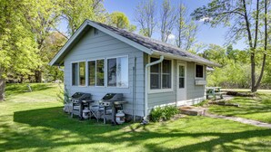 A small, single-story house with a porch, a grill, and a picnic table. - Hackensack Waterfront Retreat on Tenmile Lake (Hackensack)