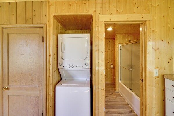 A compact room with a washing machine, a door, and a shower area.