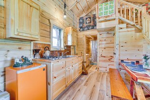 A wooden cabin interior with a kitchen, dining area, and a staircase.