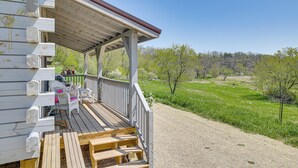 A wooden deck with outdoor seating and a view of a green landscape. - 'fins & Flowers' Off-grid Cabin w/ Trout Fishing! (Lewiston)