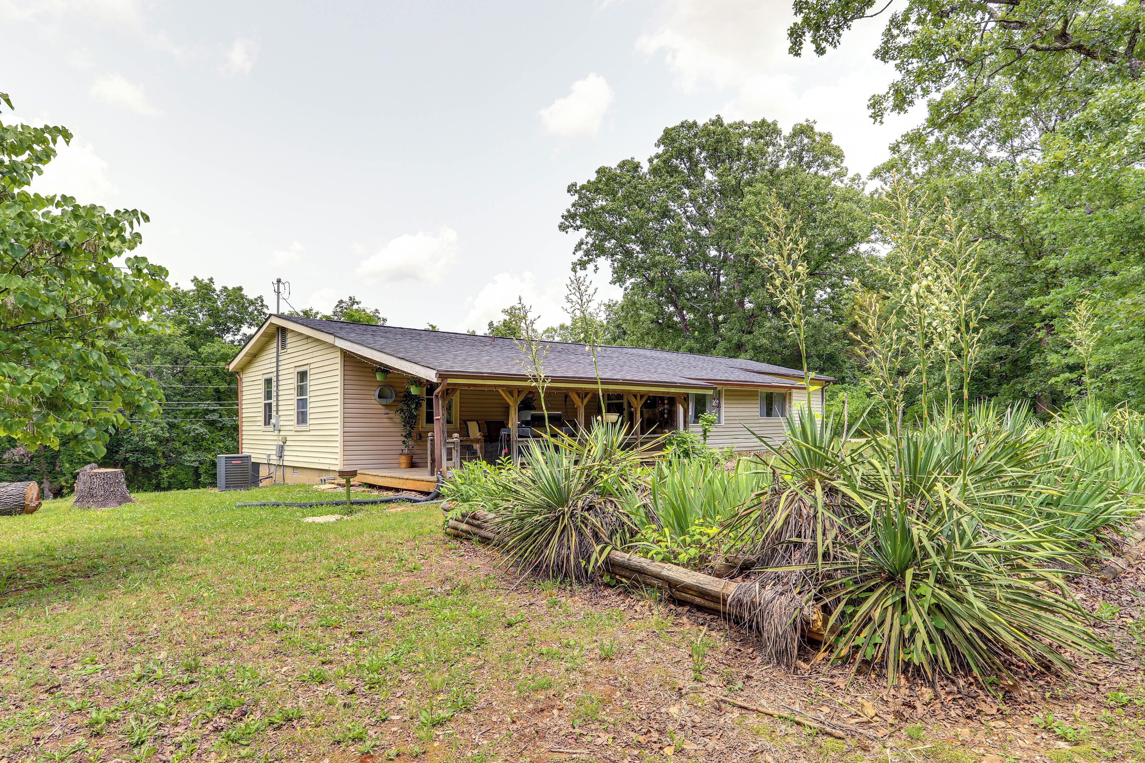 A single-story house with a porch, surrounded by a grassy yard and large agave plants.