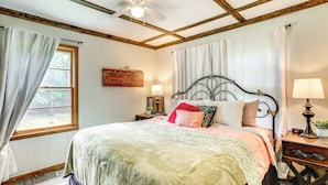 A bedroom with a bed, a nightstand, a lamp, a ceiling fan, and a window with curtains. - < 1/2 Mi to Lake: Secluded Gem in Cherokee Village (Cherokee Village)