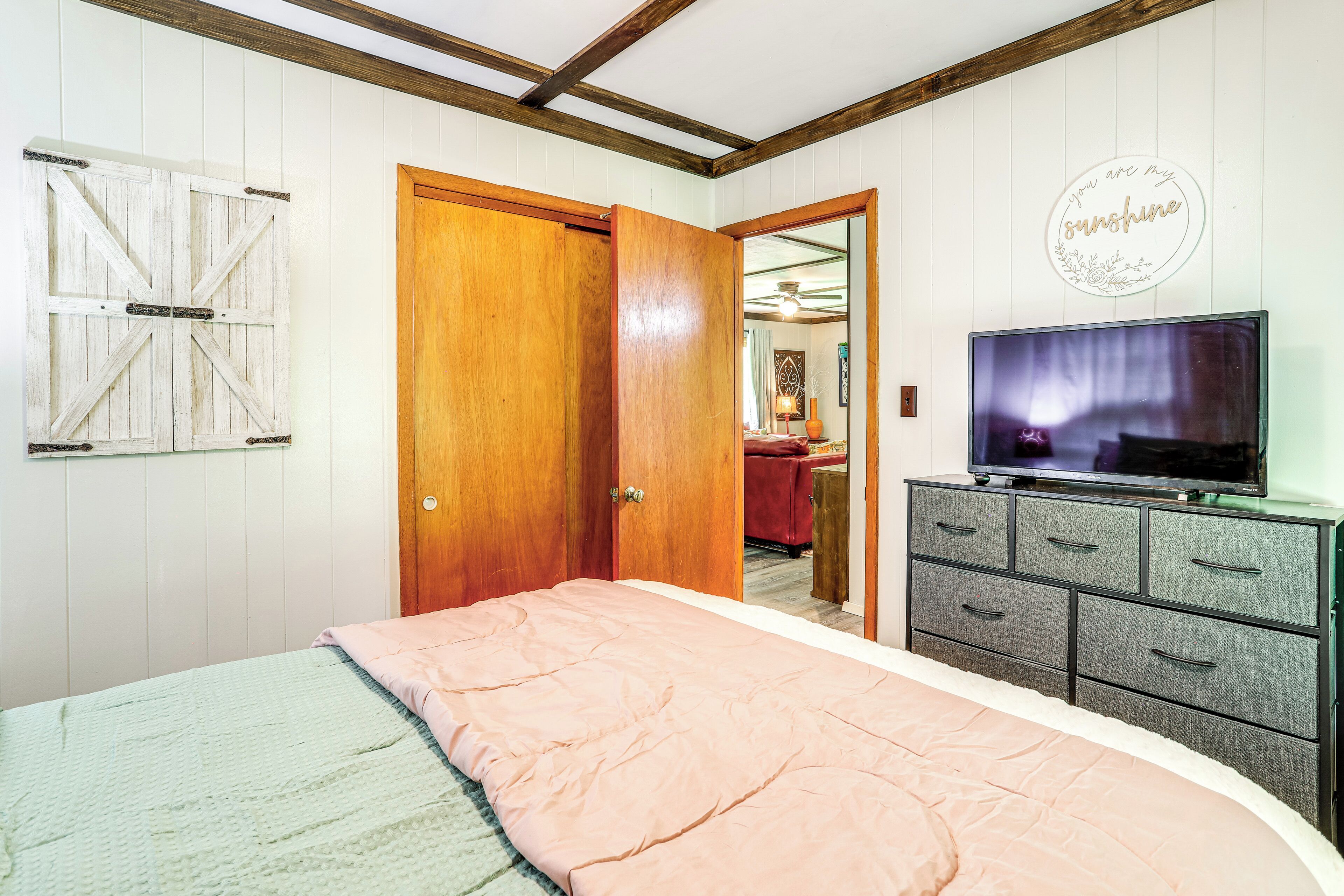 A bedroom with a bed, wooden wardrobe, and a television.