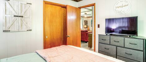 A bedroom with a bed, wooden wardrobe, and a television.