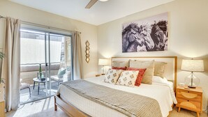 A bedroom with a bed, bedside tables, a ceiling fan, a window with curtains, and a wall-mounted artwork. - Family-friendly Condo w/ Pool Access in Phoenix! (Phoenix)