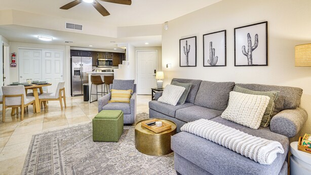 A living room with a grey sofa, a green ottoman, a round coffee table, and a ceiling fan. - Family-friendly Condo w/ Pool Access in Phoenix! (Phoenix)