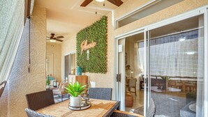 An outdoor patio area with wicker furniture, a wooden table, and a potted plant. - Family-friendly Condo w/ Pool Access in Phoenix! (Phoenix)