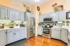 A kitchen with light gray cabinets, stainless steel appliances, and a wooden floor. - Hot Tub & Fire Pit: Rockbridge Getaway! (Rockbridge)