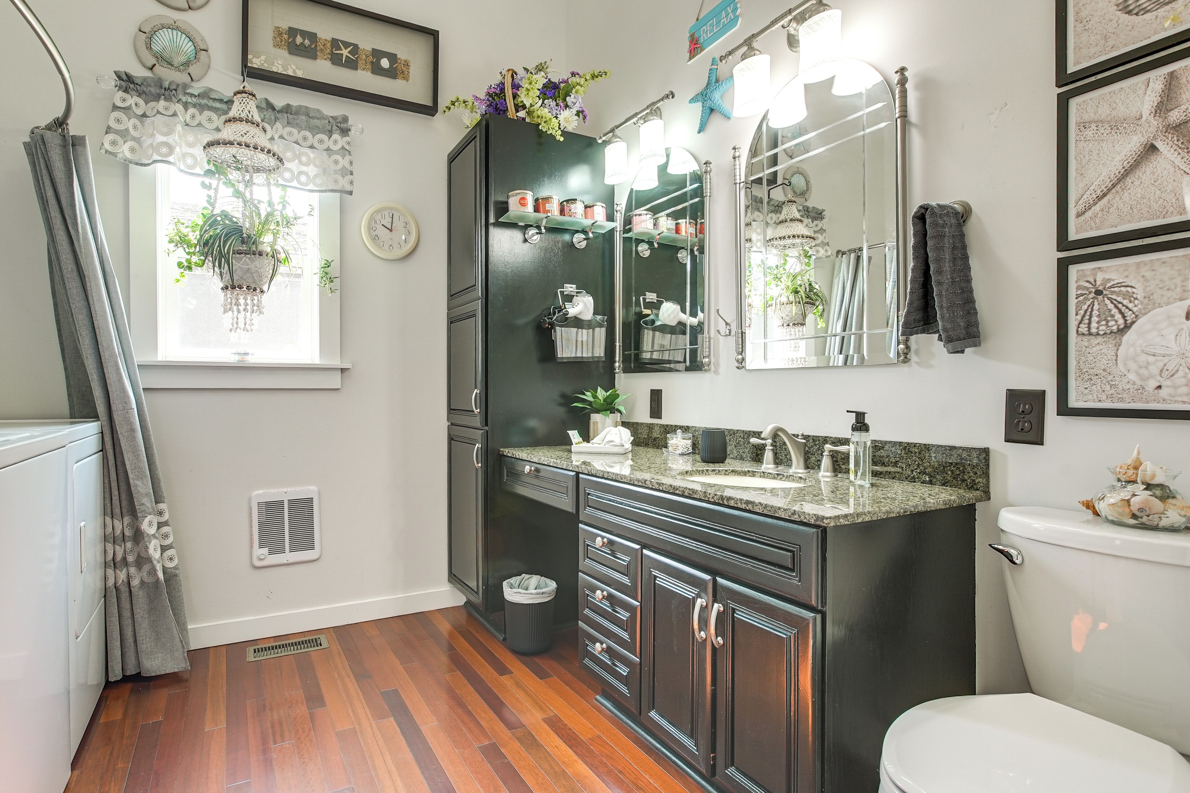 A bathroom with dark cabinetry, a vanity with a granite countertop, a large mirror, and a toilet.