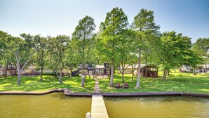 A dock extending into a body of water with a grassy area and trees in the background. - Live Lake Life! Enchanted Oaks Gem w/ Private Dock (Mabank)