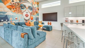 A modern living room with a large sofa, a coffee table, and a mural on the wall.