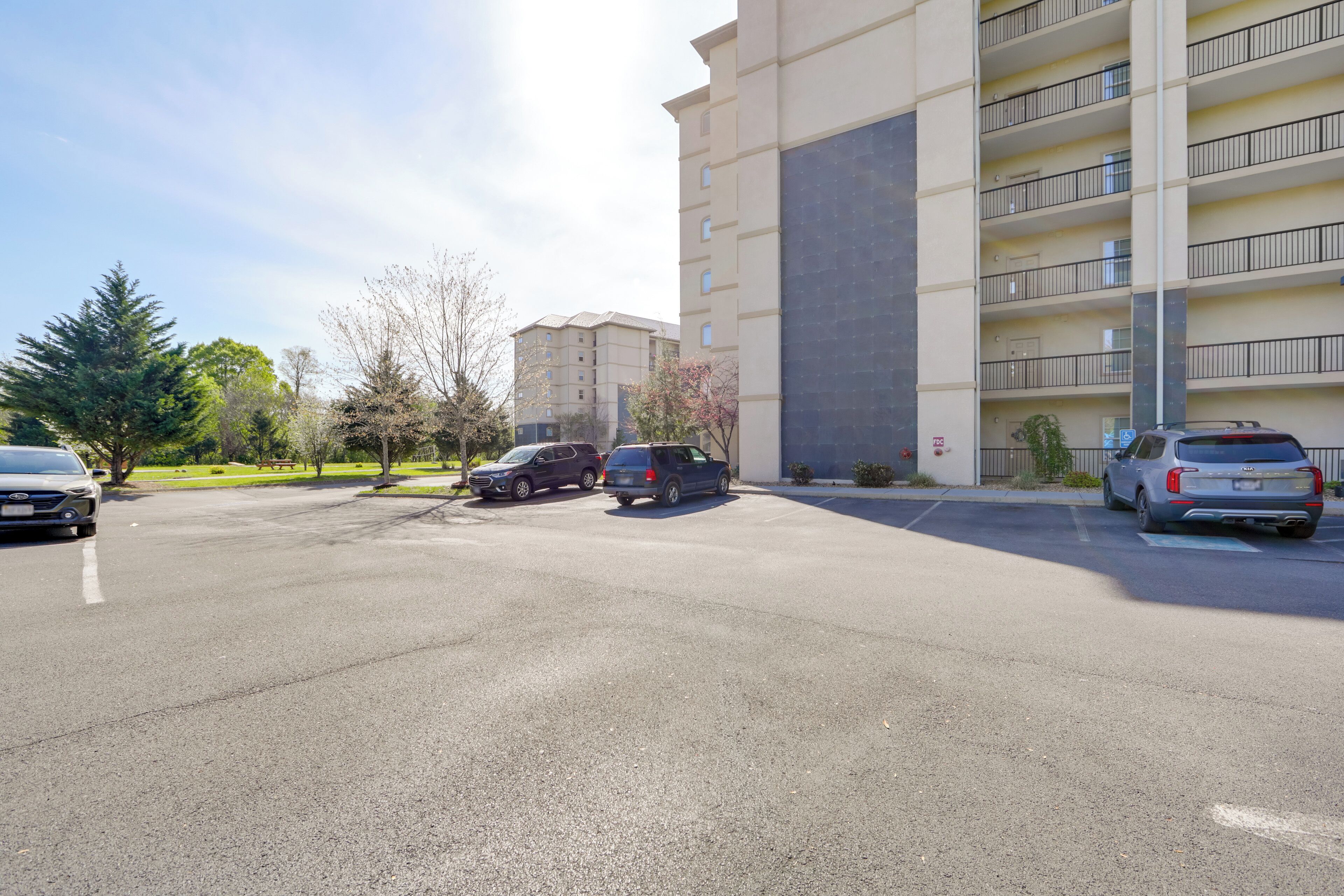 A parking lot with several cars, a multi-story building with balconies, and a clear sky.