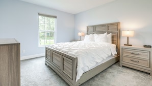 Un dormitorio con cama, mesitas de noche y cómoda.