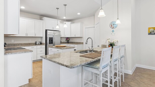 A modern kitchen with white cabinets, granite countertops, and pendant lighting. - 10 Golden Eagle Dr, Ocean View, DE (Ocean View)