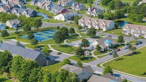 An aerial view of a residential neighborhood with houses, roads, and a large blue parking lot. - 10 Golden Eagle Dr, Ocean View, DE (Ocean View)