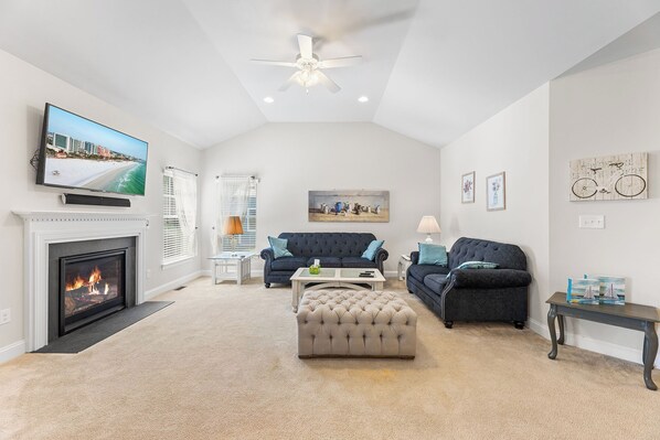 A spacious living room with a fireplace, a television, and a ceiling fan. - 10 Golden Eagle Dr, Ocean View, DE (Ocean View)