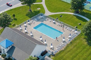 An aerial view of a swimming pool area with lounge chairs, umbrellas, and a building with a blue roof. - 10 Golden Eagle Dr, Ocean View, DE (Ocean View)