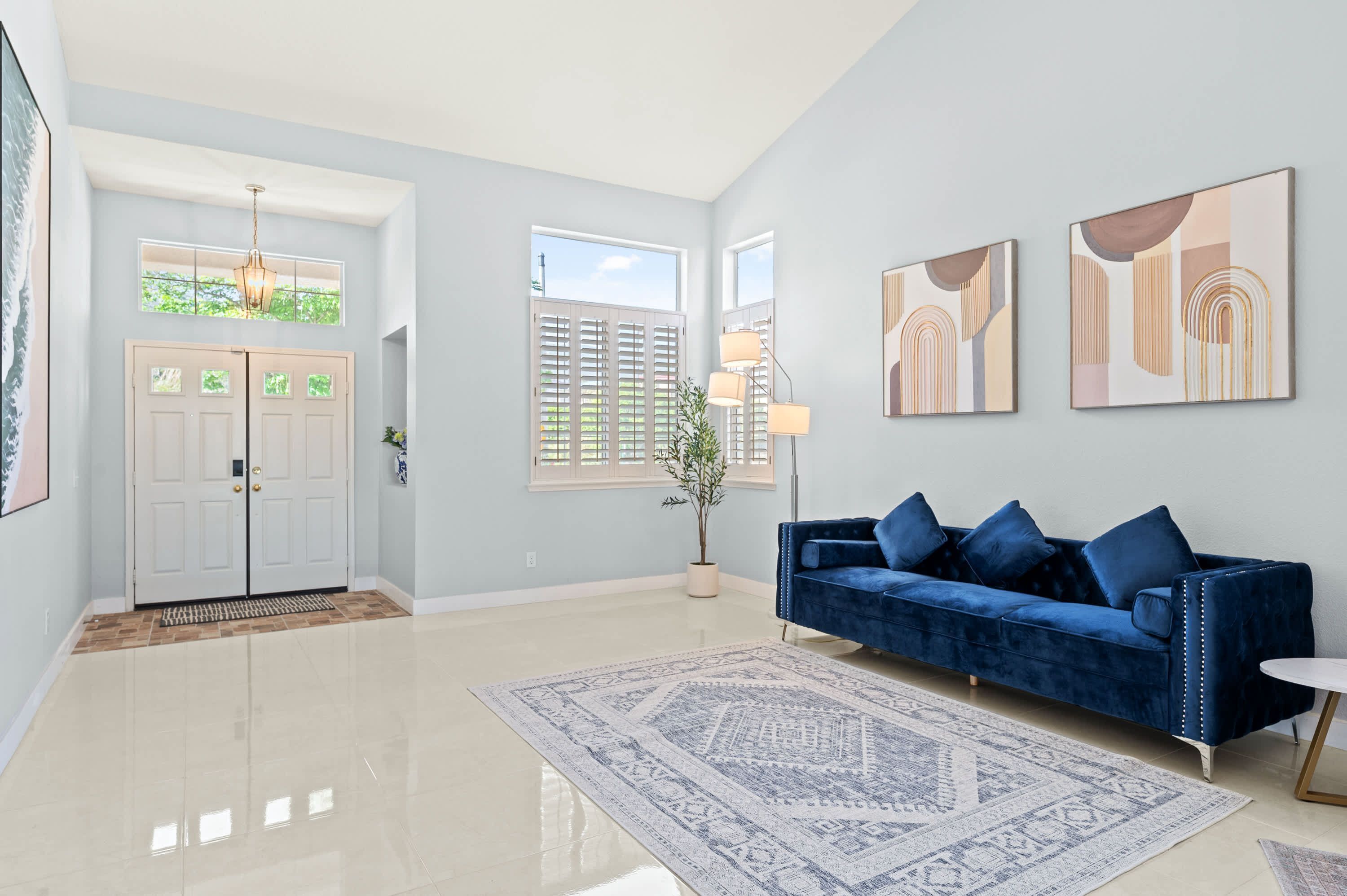 A spacious living room with a blue sofa, a patterned rug, and artwork on the walls.