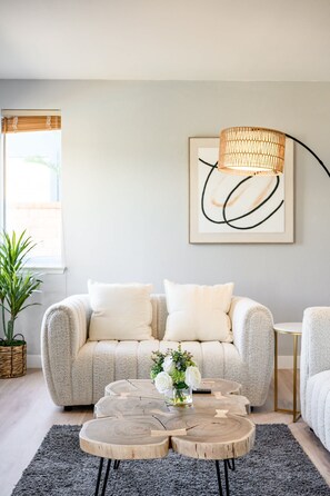 A living room with a sofa, a coffee table, and a hanging light fixture.