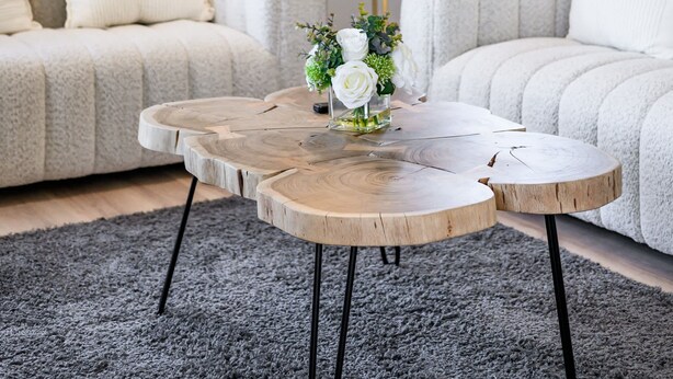 Una sala de estar moderna con un sofá gris, una mesa de centro redonda de madera y una lámpara de pie.