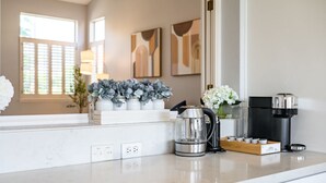 Una cocina moderna con encimera de mármol, cafetera y jarrones decorativos.