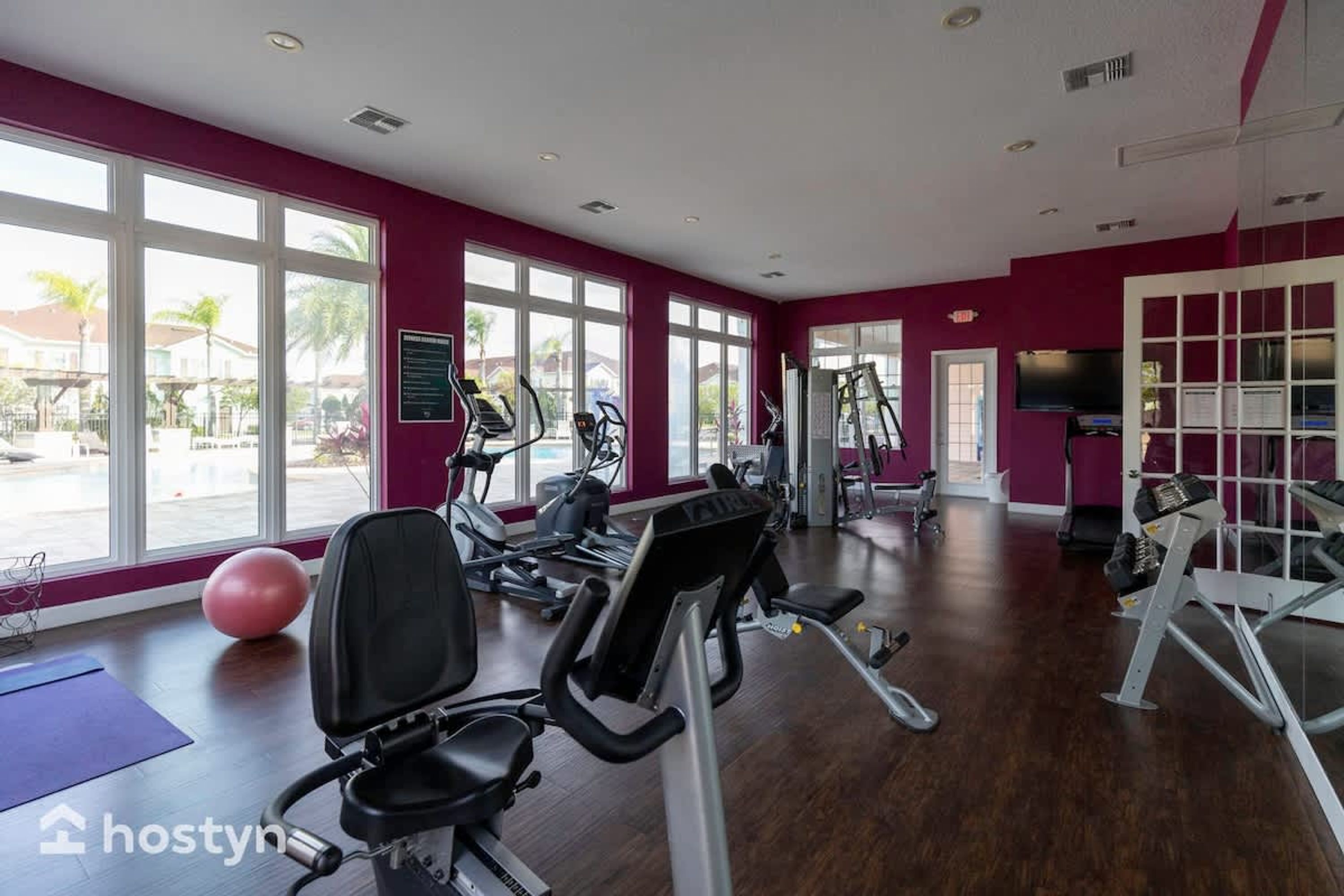 A gym with cardio machines, weights, and a large window.