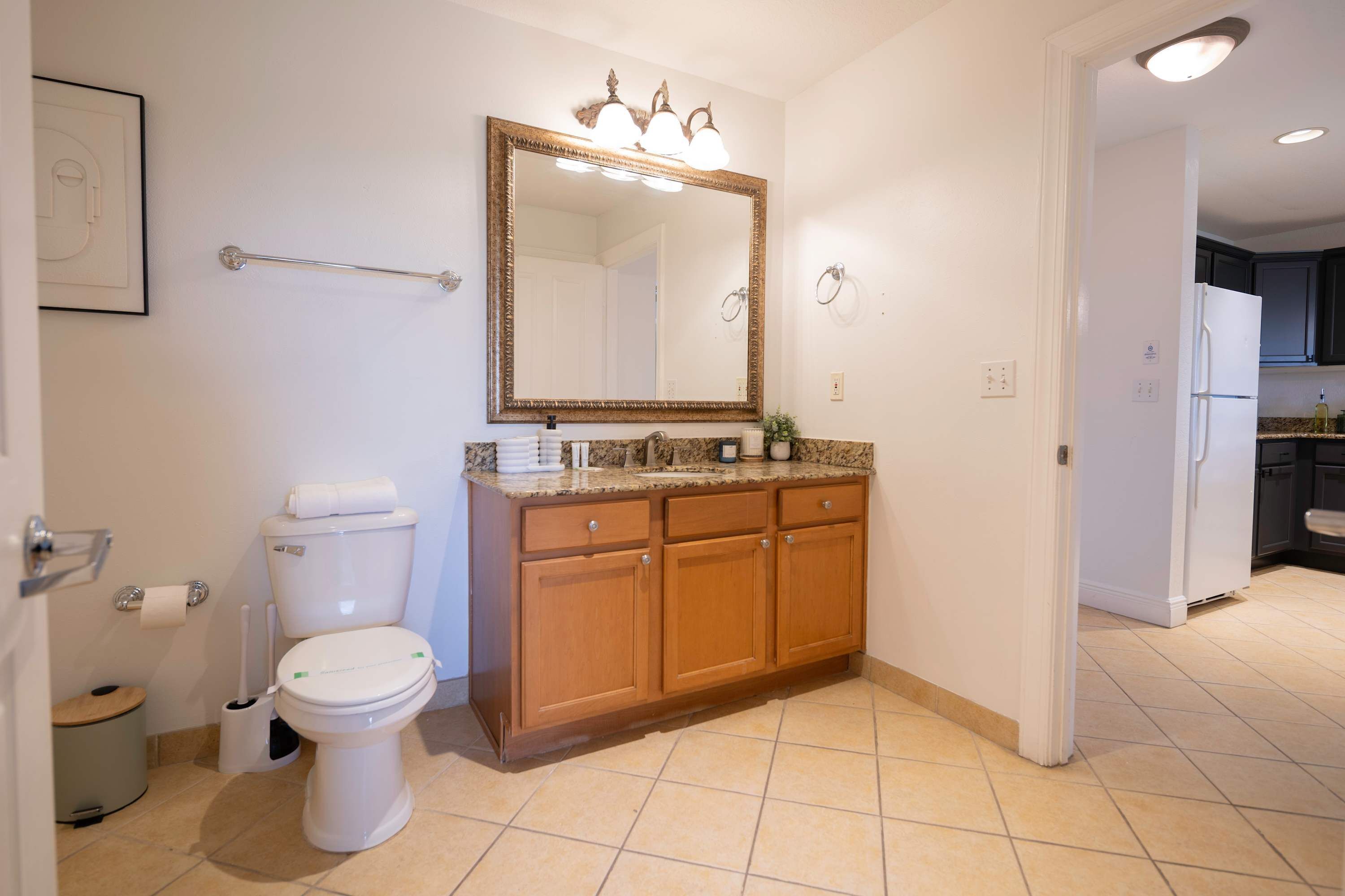 A bathroom with a toilet, sink, vanity, and a large mirror.