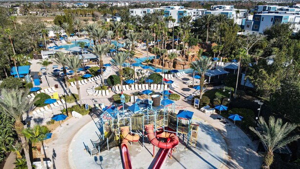 Vista aérea de un resort con varias piscinas, tumbonas y palmeras.