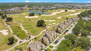 Un campo de golf con bunkers de arena, un estanque y una zona residencial con casas adosadas.