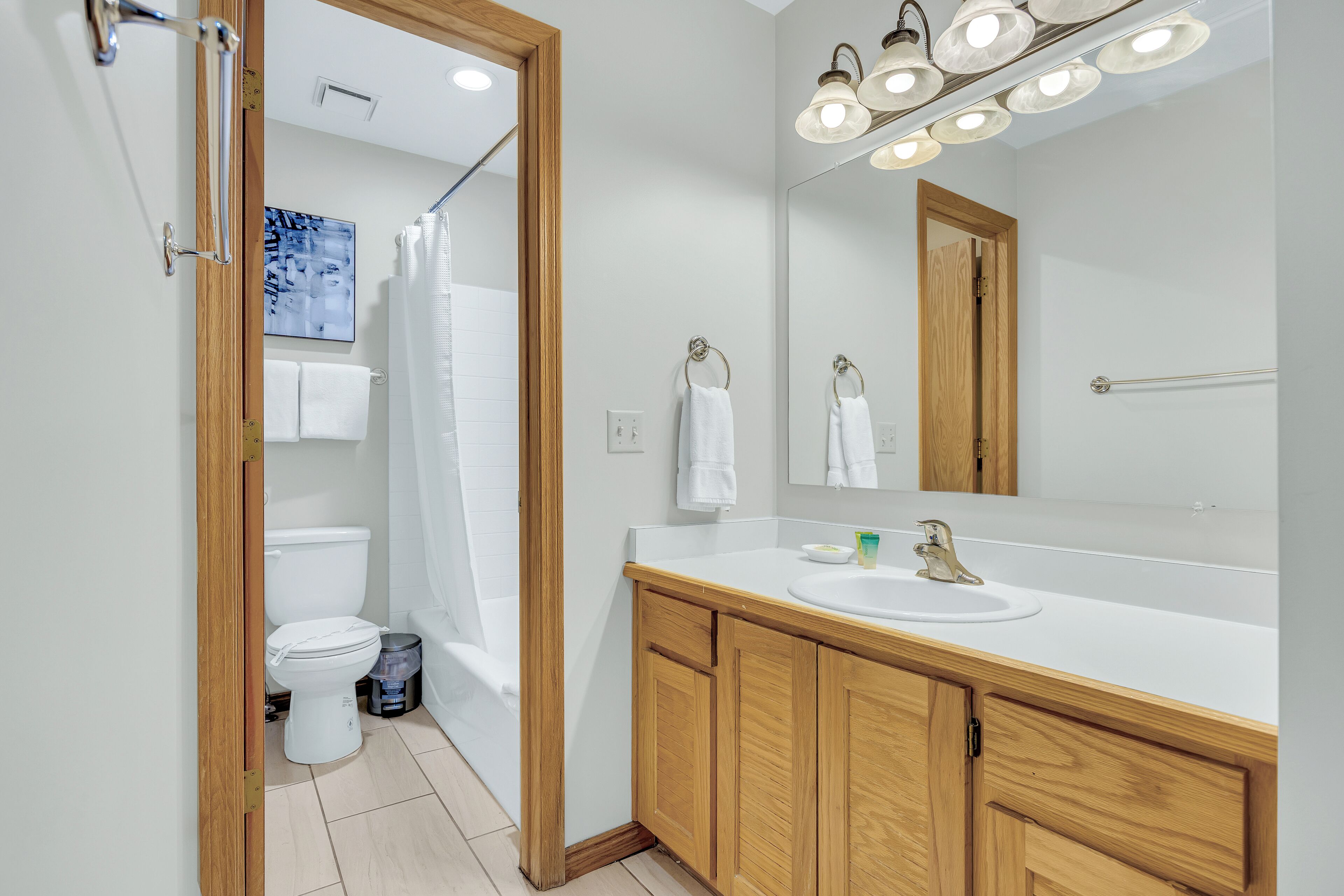 A modern bathroom with a wooden vanity, a white sink, and a large mirror.
