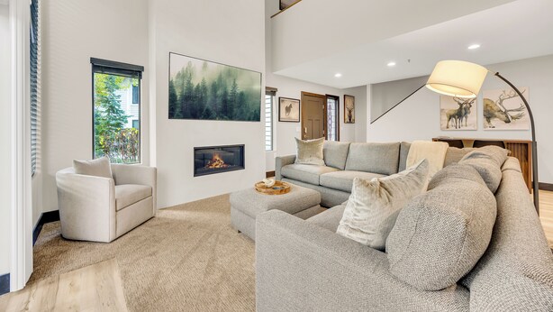 A modern living room with a sectional sofa, a fireplace, and artwork on the walls.