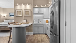 A modern kitchen with a central island, grey cabinets, and stainless steel appliances.